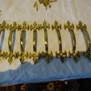 May include: Eight gold-toned door handles with a decorative, ornate design. Each handle has a pointed, spear-like shape at the top and bottom.