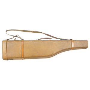 Può includere: Un fodero per fucile in pelle marrone con una tracolla. Il fodero ha una maniglia e una fibbia.