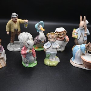 Könnte beinhalten: Eine Sammlung von Keramikfiguren, die verschiedene Tierfiguren darstellen. Die Figuren umfassen einen Mann mit einer Laterne, ein Eichhörnchen, eine Ente, einen Bären, einen Igel, ein Kaninchen, eine Maus und eine weitere Maus mit einer Schüssel. Die Figuren sind in verschiedenen Farben bemalt.
