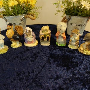 Könnte beinhalten: Eine Sammlung von Keramikfiguren mit verschiedenen Tierfiguren, darunter ein Hahn, ein Frosch und eine Maus. Die Figuren sind farbenfroh und detailliert gestaltet. Sie sind auf einer dunkelblauen Oberfläche angeordnet.