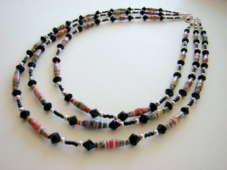 May include: A three-strand necklace with black and multi-colored paper beads and black faceted beads.