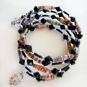 May include: Multi-strand bracelet with black beads, silver beads, and colorful paper beads. The bracelet has a heart-shaped charm with rhinestones.