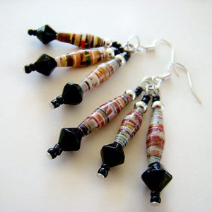 May include: A pair of earrings with black and silver beads and colorful paper beads. The earrings are made with recycled paper and are a unique and stylish accessory.