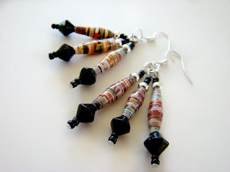 May include: A pair of earrings with black and silver beads and colorful paper beads. The earrings are made with recycled paper and are a unique and stylish accessory.