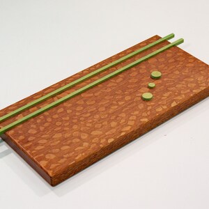 May include: A rectangular wooden tray with a green patterned surface. The tray has two green wooden strips running across the top and three green circles in a vertical line.