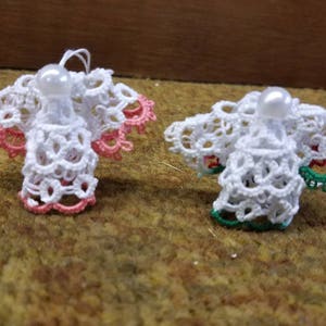 May include: Two white crocheted angel ornaments with pearl beads. One angel has pink trim and the other has green trim.