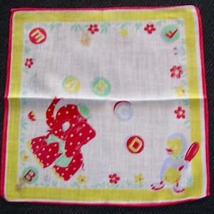 May include: White handkerchief with a yellow border and red trim. The handkerchief features a red elephant with white polka dots, a yellow duck with a red paddle, and colorful circles and flowers. The letters A, B, C, and E are in circles.