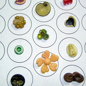 Puede incluir: Una colección de botones vintage en varias formas y colores, incluyendo diseños florales, de hojas y abstractos. Los botones se muestran en círculos blancos individuales, mostrando sus detalles y texturas únicos. Los colores incluyen tonos de marrón, verde y rojo.