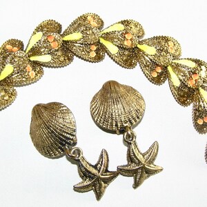 May include: A gold-tone bracelet with a delicate design of interlocking hearts, accented with light yellow and orange enamel. Matching earrings feature a seashell design with a dangling starfish.