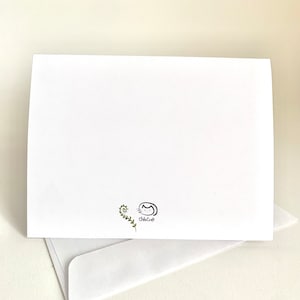 Op de afbeelding: Lege blanco kaart met een kleine groene wijnstok en een zwart-witte illustratie van een kat met de tekst "chicacat" eronder.