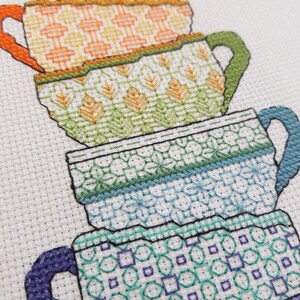 Puede incluir: Una pila de cinco tazas de t&eacute; de colores con diferentes dise&ntilde;os de patrones. Las tazas est&aacute;n apiladas de la m&aacute;s grande a la m&aacute;s peque&ntilde;a, con la taza m&aacute;s grande en la parte inferior y la taza m&aacute;s peque&ntilde;a en la parte superior. Las tazas son todas blancas con diferentes patrones de colores. Los patrones incluyen formas geom&eacute;tricas, flores y rayas.