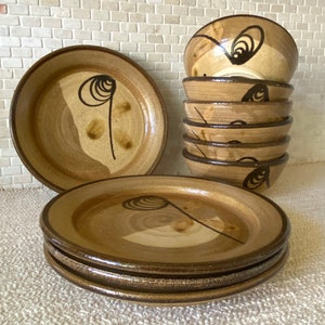 May include: Set of six brown ceramic bowls with a swirl design. The bowls are stacked on top of each other. There are also two brown ceramic plates with a swirl design.