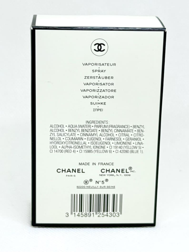 May include: A rectangular white perfume box with black trim featuring the Chanel logo at the top. The text includes the word spray in multiple languages, a detailed list of ingredients, the Chanel Paris and New York addresses, and a barcode.
