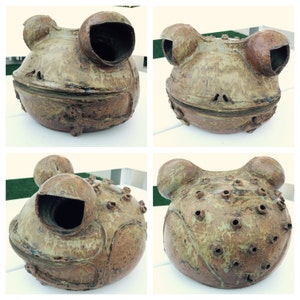 May include: Four ceramic frog sculptures with a speckled brown and green glaze. Each frog has a unique design with holes and a hollow interior.