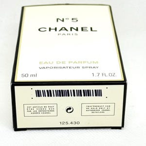May include: A rectangular Chanel No. 5 Eau de Parfum box in white with black trim. The front displays the text N&deg; 5 CHANEL PARIS, EAU DE PARFUM, VAPORISATEUR SPRAY, 50 ml, and 1.7 FL.OZ. The bottom edge features a barcode and retail text.