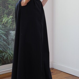 May include: A black high-waisted maxi skirt with a wide waistband and a flowing silhouette.