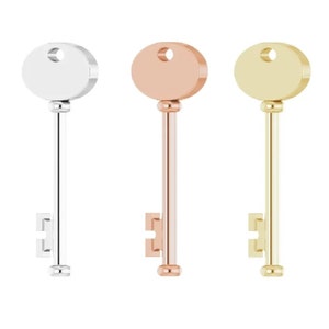 May include: Three key-shaped charms in silver, rose gold, and gold finishes. Each charm features a rounded oval head with a keyhole and a simple key design.