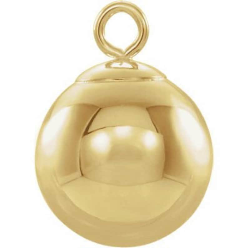 May include: A gold-toned ball charm with a loop at the top. The ball is smooth and shiny.