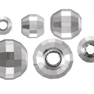 May include: A set of six silver-toned faceted metal beads with a hole in the center. The beads are different sizes and have a shiny finish.