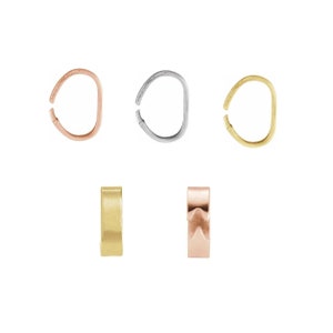 May include: Set of five gold, silver, and rose gold jump rings. The jump rings are oval shaped and have a smooth finish. Two of the jump rings are open and three are closed.