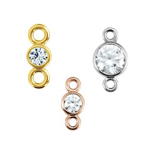 May include: Three connector charms with a single round clear crystal in the center of each. The charms are in gold, silver, and rose gold.