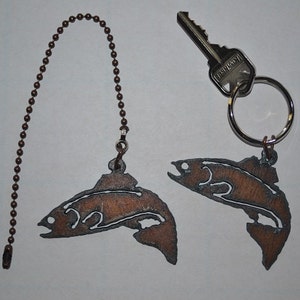 May include: Two metal fish charms, one on a brown chain and the other on a silver key ring. The fish are brown and have a detailed silhouette design.