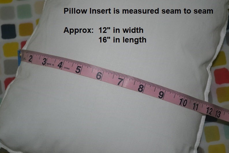 May include: A white pillow insert with a pink measuring tape across it. The tape reads "2 3 4 5 6 7 8 9 10 11 12 13". Text on the pillow reads "Pillow Insert is measured seam to seam Approx: 12" in width 16" in length"