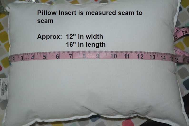 May include: A white pillow insert with a pink measuring tape across it. The text on the pillow reads "Pillow Insert is measured seam to seam Approx: 12" in width 16" in length".