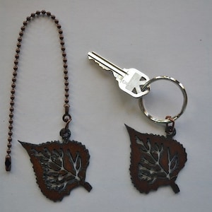 May include: Two copper leaf-shaped keychains with a chain and a key on a white background.