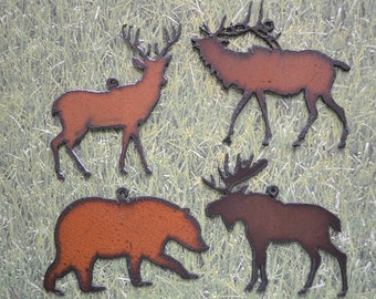 May include: Four metal animal silhouettes in rusty brown and black colors. The silhouettes are of a deer, elk, moose, and bear. The animals are all facing to the right. The silhouettes are on a green background.