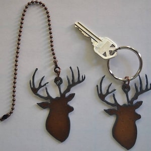 May include: Two brown metal deer head fan pull chains with a copper chain. The chains are attached to a key ring with a silver key.