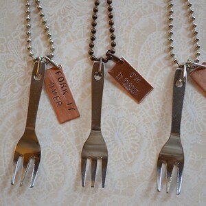 May include: Three silver forks on chains with copper tags. The tags have the phrases "Fork It Over", "I'm Done", and "What The..." engraved on them.