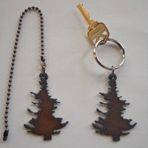 May include: Two rustic brown metal Christmas tree ornaments. One is attached to a copper chain and the other is attached to a silver key ring.