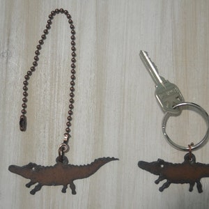 May include: Two alligator-shaped metal pulls, one attached to a copper chain and the other to a silver key ring. The alligator pulls are a dark brown color.