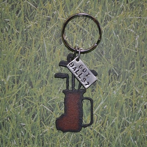 May include: A metal golf bag keychain with a silver tag that reads 