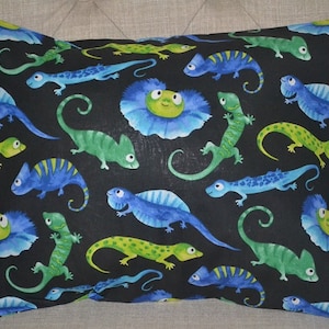 May include: A black pillowcase with a repeating pattern of blue and green lizards and flowers. The lizards are in various poses, some with their tongues out. The flowers are blue with green centers.