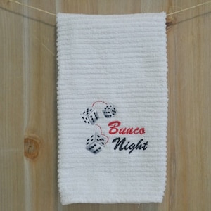 May include: White kitchen towel with red and black embroidery of dice and the text "Bunco Night".