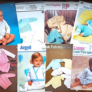 Op de afbeelding: Een verzameling vintage breipatronenboekjes voor baby's. De covers tonen afbeeldingen van baby's in gebreide truien, vesten en outfits. De boekjes zijn in verschillende kleuren, waaronder blauw, roze en geel. Sommige boekjes hebben tekst zoals "Studley" en "Baby Copley".