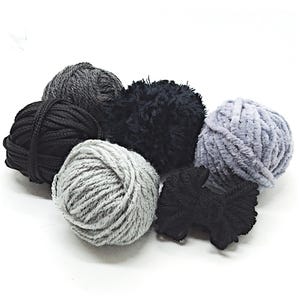 May include: A selection of yarn balls in shades of grey and black. Textures range from smooth to fluffy, with some having a slight sheen. Suitable for knitting and crochet projects.