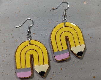 May include: A pair of dangle earrings shaped like yellow pencils bent into an arch. Each earring features a silver-toned metal hook, a yellow pencil body with black lines, a grey ferrule, a pink eraser, and a pointed black pencil tip.