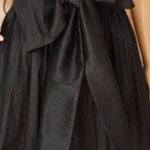 May include: A black skirt with a large black satin bow at the waist.