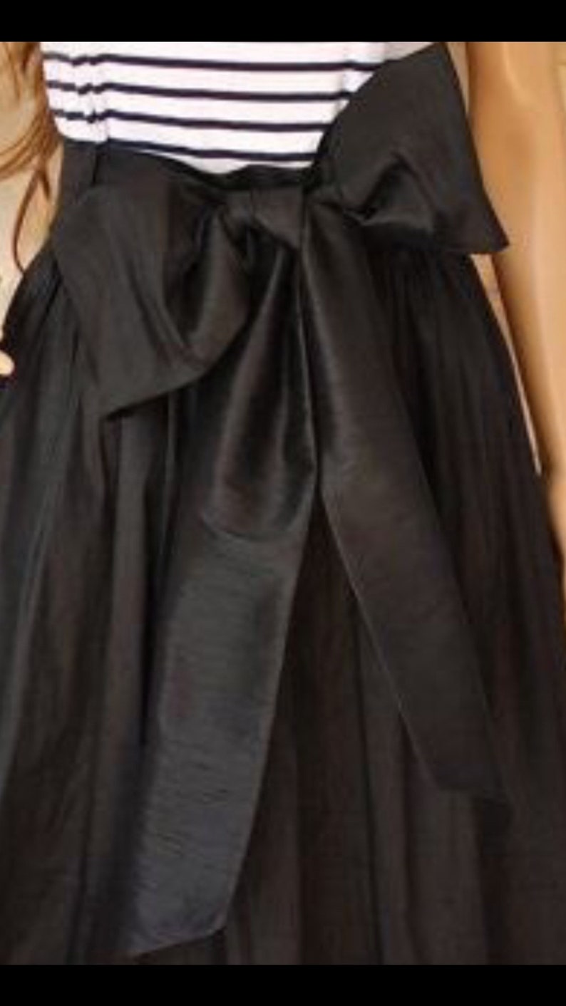 May include: A black skirt with a large black satin bow at the waist.