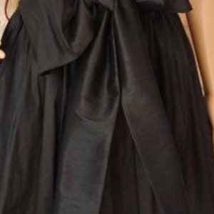 May include: A black skirt with a large black satin bow at the waist.