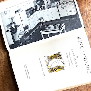 May include: A black and white photo of a kitchen with white cabinets and appliances. The caption reads "Poor equipment cannot cramp the style of a good cook, but even a poor cook can develop a good style in an all-electric kitchen."