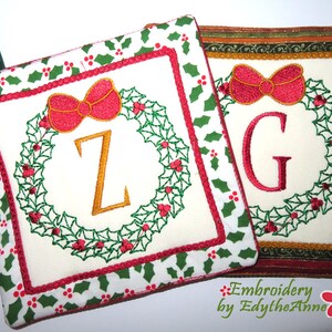 May include: Two embroidered Christmas pot holders with a holly wreath design. One pot holder features the letter "Z" and the other features the letter "G". Both pot holders have a red and green holly pattern on the back.