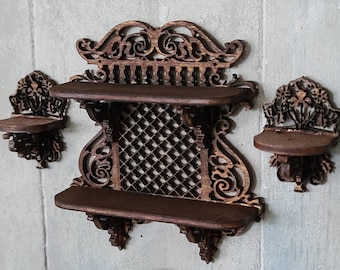 May include: A set of three ornate wooden wall shelves with intricate carvings and a lattice design. The shelves are dark brown and have a distressed finish.
