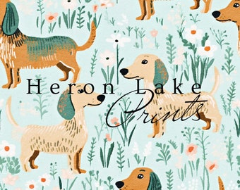 May include: A seamless pattern featuring a repeating design of brown and green dachshunds with white flowers and green foliage on a light blue background. The text "Heron Lake Prints" is visible in the centre of the design.