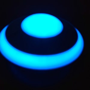 K&ouml;nnte beinhalten: Ein blaues, leuchtendes Licht mit einem kreisf&ouml;rmigen Design. Das Licht hat die Form eines Rings mit einem kleineren Kreis in der Mitte.