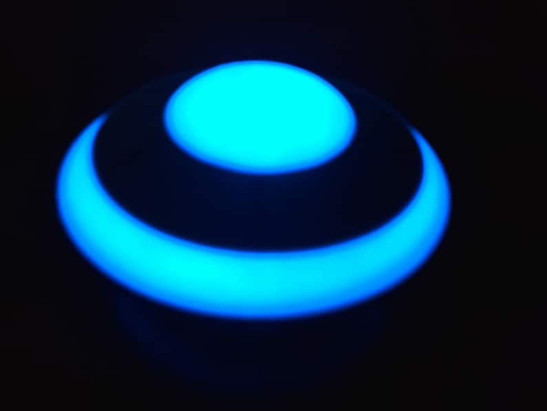 K&ouml;nnte beinhalten: Ein blaues, leuchtendes Licht mit einem kreisf&ouml;rmigen Design. Das Licht hat die Form eines Rings mit einem kleineren Kreis in der Mitte.