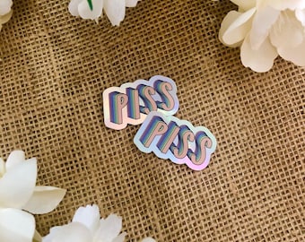 Peut inclure: Deux autocollants holographiques irisés avec le mot "PISS" en lettres arc-en-ciel. Les autocollants sont sur un fond de toile de jute brune.